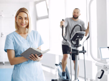 A woman is a physiotherapist. A man is using a spin bike. The patient is having a treatment.